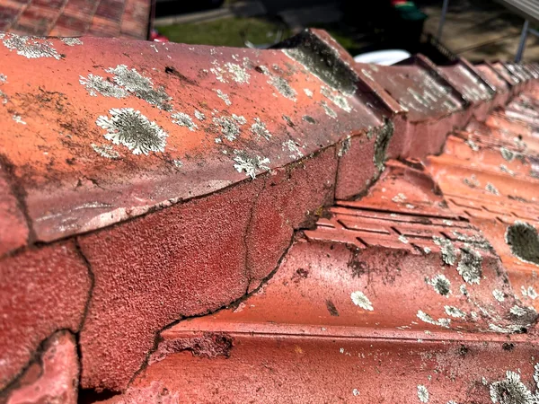 Cracked and lichen-covered ridge capping on a Sutherland Shire tile roof