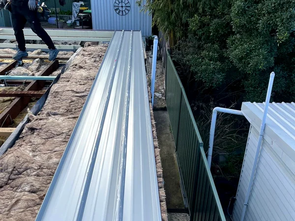 Metal roof replacement underway, new sheeting going on over the old roof